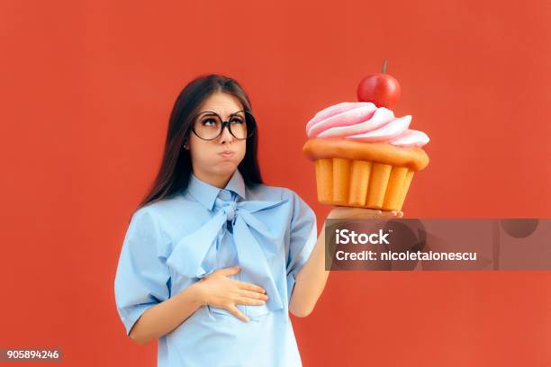 Woman Suffering Stomach Ache After Eating Too Much Cupcake Stock Photo - Download Image Now