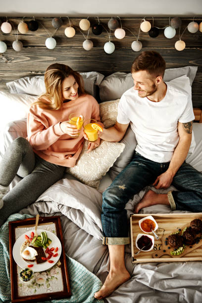 coppia felice che sta facendo colazione a letto - women juice drinking breakfast foto e immagini stock