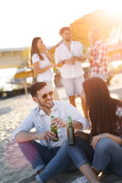 istock Happy couple smiling and drinking beer at beach 905896870