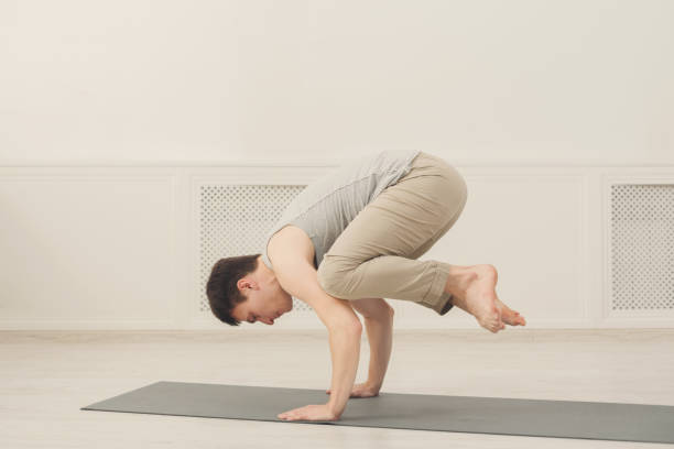 istock Young man standing in Bakasana exercise 905897460