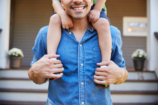 istock Father Giving Son Ride On Shoulders Outside House 905898956