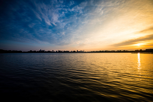 panoramic view of a Rotterdam city skyline from a lakeside, in the evening