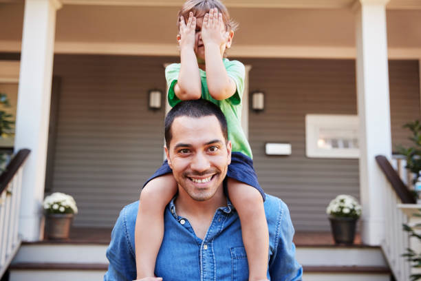 istock Father Giving Son Ride On Shoulders Outside House 905898974