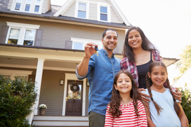 Portrait Of Family Holding Keys To New Home On Moving In Day Portrait Of Family Holding Keys To New Home On Moving In Day young family stock pictures, royalty-free photos & images