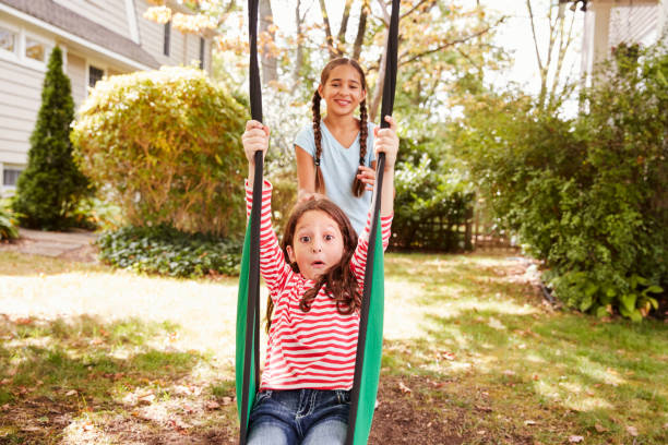 istock Two Sisters Having Fun On Garden Swing At Home 905901736
