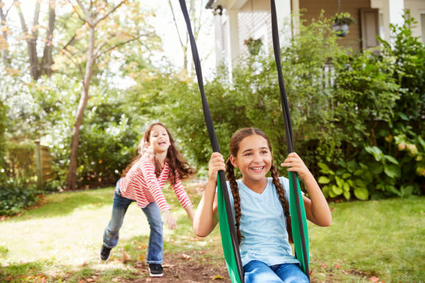 istock Two Sisters Having Fun On Garden Swing At Home 905901814