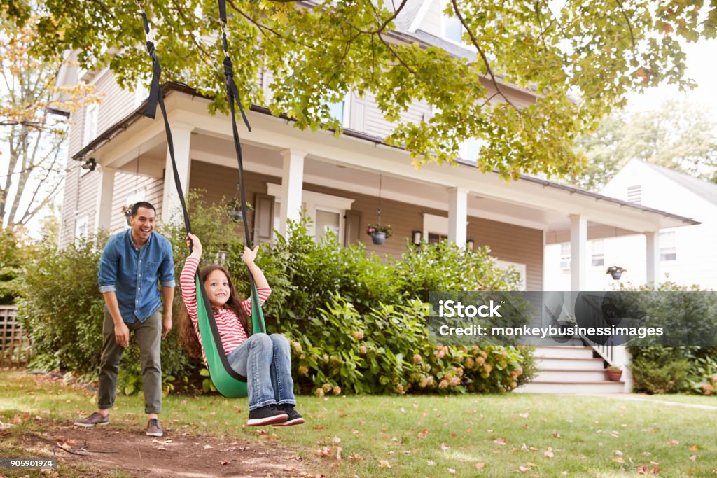 Father Pushing Daughter On Garden Swing At Home Family Stock Photo