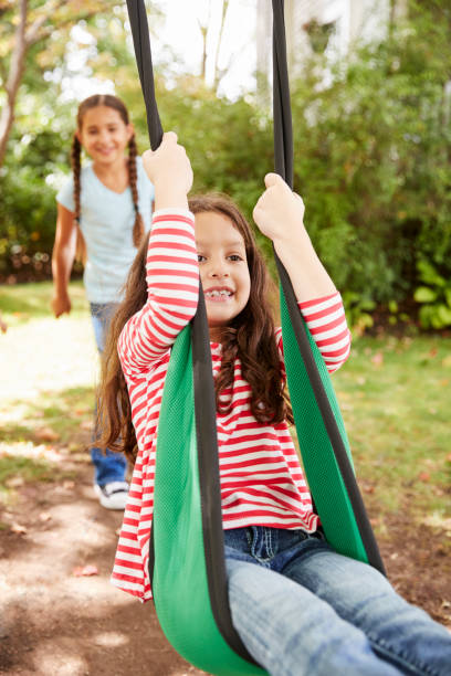 istock Two Sisters Having Fun On Garden Swing At Home 905902052
