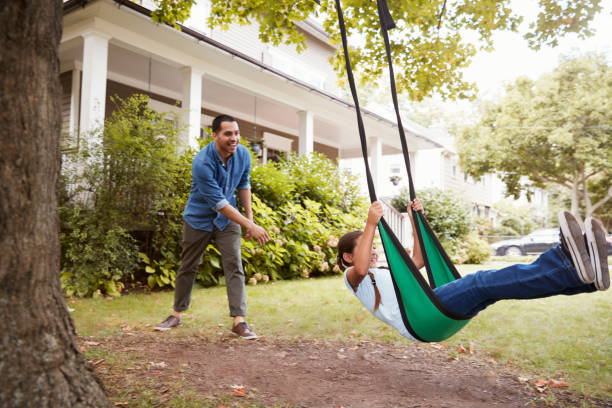 istock Father Pushing Daughter On Garden Swing At Home 905902106