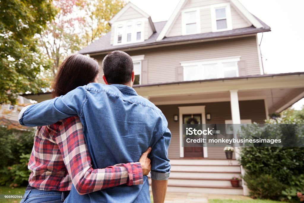 Rear View Of Loving Couple Looking At House Home Ownership Stock Photo