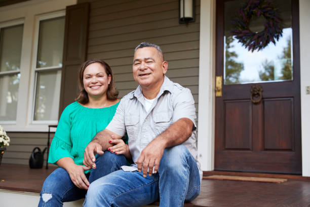 retrato de sonriente pareja senior sentado frente a su casa - day in the life fotografías e imágenes de stock