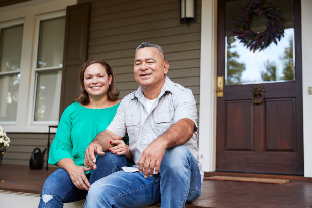 Portrait Of Smiling Senior Couple Sitting In Front Of Their Home Portrait Of Smiling Senior Couple Sitting In Front Of Their Home porch stock pictures, royalty-free photos & images