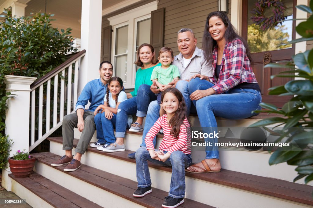 Multi geração familiar sente-se em etapas que antecederam a varanda de casa - Foto de stock de Família de várias gerações royalty-free