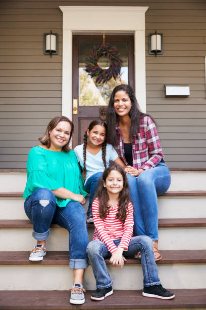 istock Female Multi Generation Family Sit On Steps in Front Of House 905902510