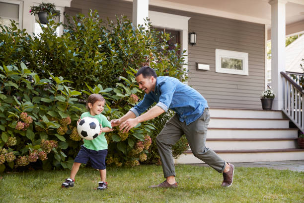 pai jogando futebol no jardim com o filho - running family father child - fotografias e filmes do acervo