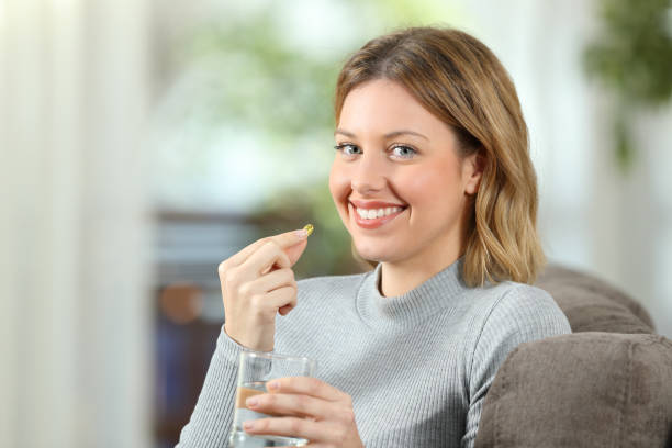 Woman posing holding a vitamin pill ready to take