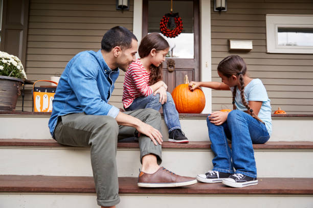 istock Father And Daughters Drawing Face On Halloween Pumpkin 905905202