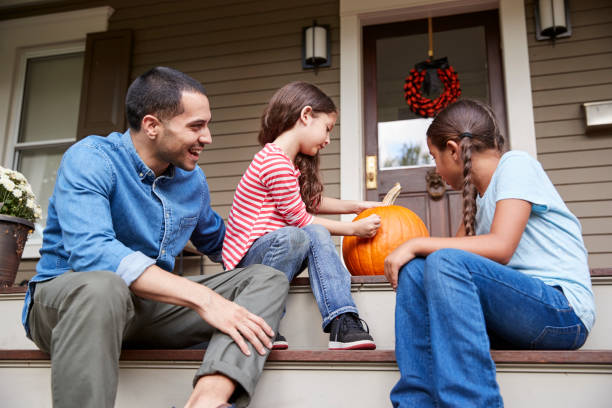 istock Father And Daughters Drawing Face On Halloween Pumpkin 905905224