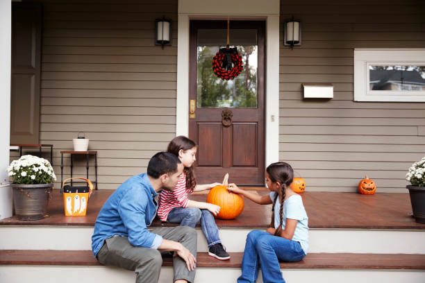 istock Father And Daughters Drawing Face On Halloween Pumpkin 905905320