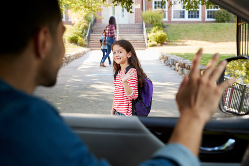 Father In Car Dropping Off Daughter In Front Of School Gates