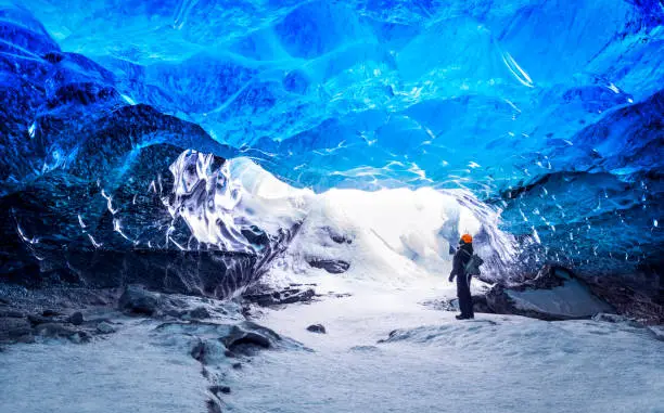 Traveler in ice cave, man standing underground inside of a glacier, climate specific, Vatnajokull National Park, amazing nature of Skaftafell, Iceland