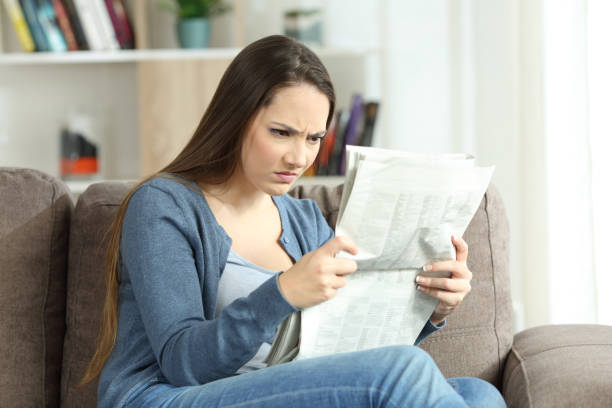 istock Angry woman reading a newspaper on a couch 905918016