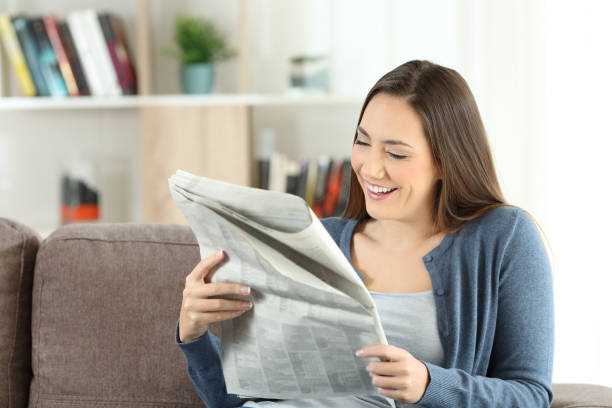 istock Happy lady reading a newspaper at home 905918348