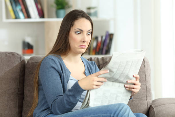 istock Confused woman reading a newspaper on a couch 905918498