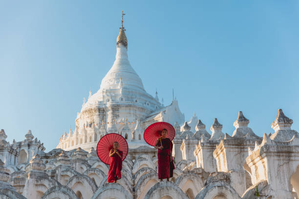 novizen unter sonnenschirmen am historischen tempel - myanmar stock-fotos und bilder