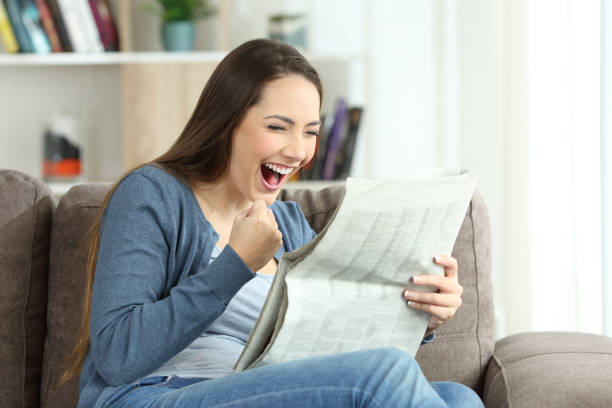 istock Excited woman reading a newspaper on a couch 905921366