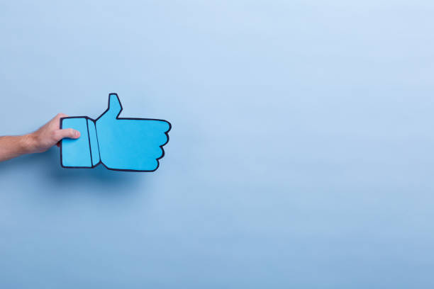 istock A man's hand holds a gesture sign with his thumb facing up. Blue background with a place for an inscription. 905926510