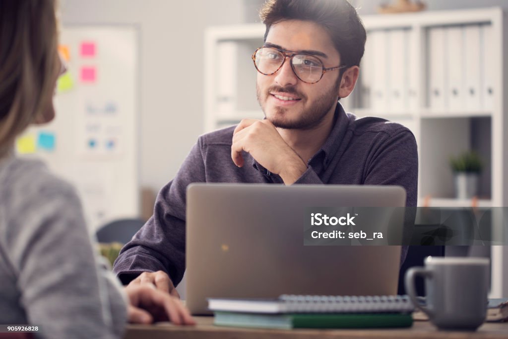 Young man listening a client in the office Casual Clothing Stock Photo