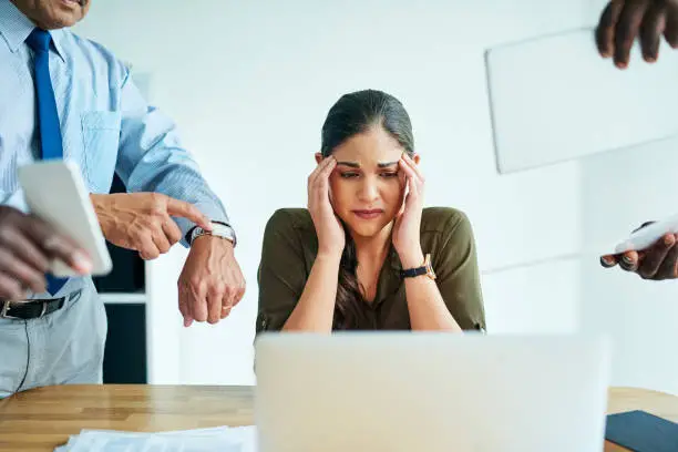 Shot of a stressed out businesswoman surrounded by colleagues needing help in an office