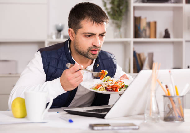istock Positive young male holding  fork, eating vegetable salad 905932602
