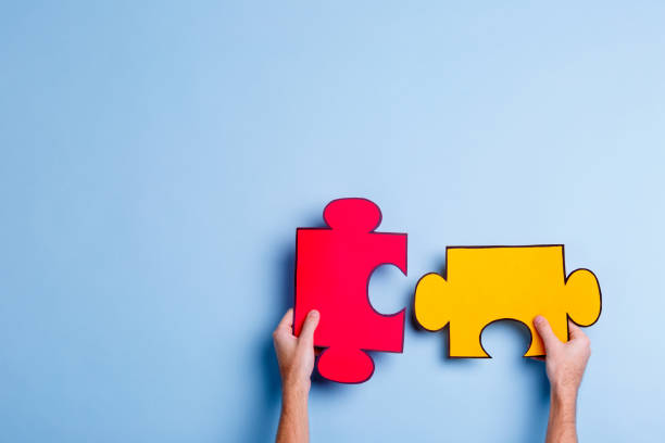 istock Hands of a man who fold two puzzles. On a blue background. Close-up. 905932786