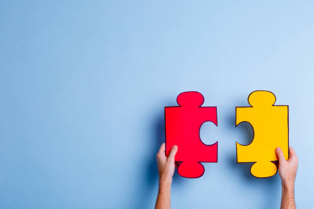 istock The hands of a man who hold puzzles. Blue background. 905932848