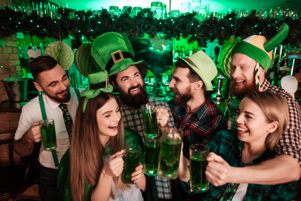 The company of young people celebrate St. Patrick's Day. The company of young people celebrate St. Patrick's Day. They have fun at the bar. They are dressed in carnival headgear. st. patricks day photos stock pictures, royalty-free photos & images