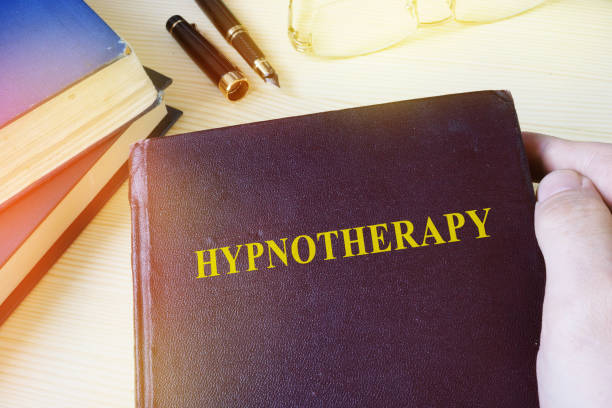 istock Man holding book with title Hypnotherapy. 905933380