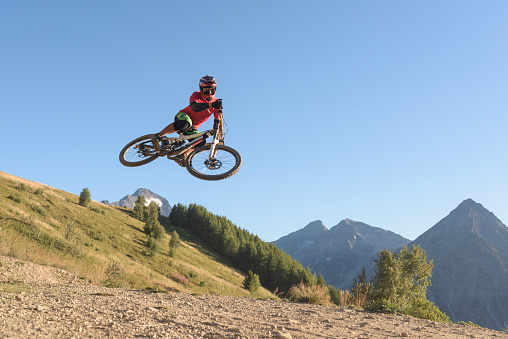 Man performing midair stunts with mountain bike outsdoor against clear blue sky