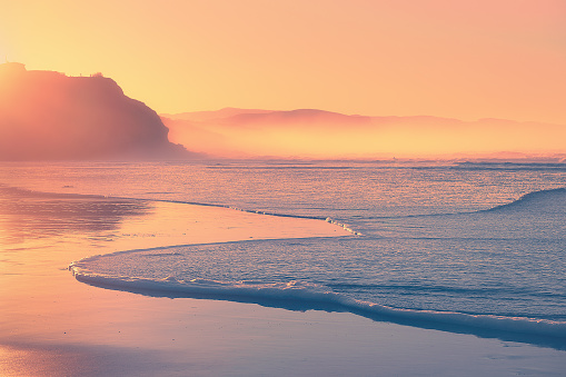 beach at sunset with wave foam on the shore