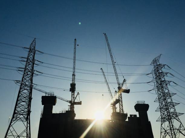 istock electricity pole with crane equipment for development construction building with lens flare from sunset in morning before worker start work. silhouette background of Industrial. 905945730