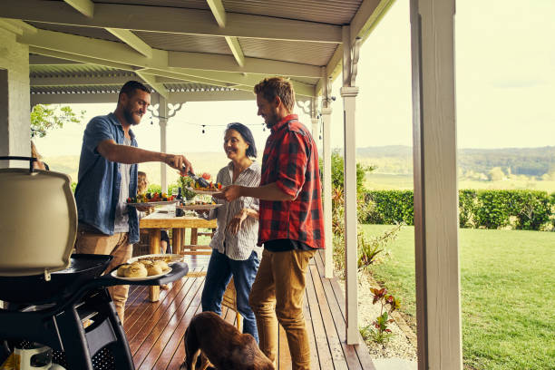 He sure knows how to host a lunch Shot of people getting food fresh off the braai traditionally australian stock pictures, royalty-free photos & images