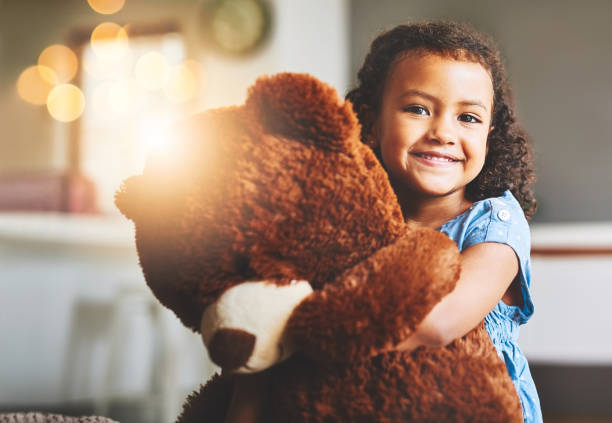I don't go anywhere without him! Portrait of a little girl holding her teddy bear at home stuffed toy stock pictures, royalty-free photos & images