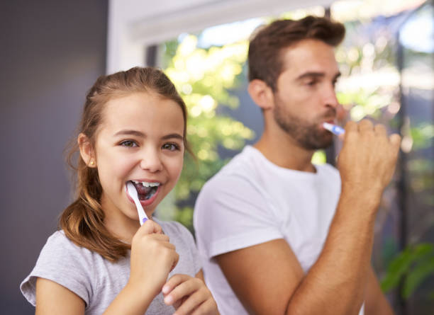Thanks to Daddy I can brush my teeth myself Cropped shot of a handsome Dad and his daughter brushing their teeth in the bathroom at home brushing teeth stock pictures, royalty-free photos & images