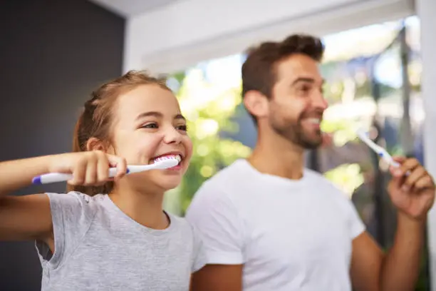Cropped shot of a handsome Dad and his daughter brushing their teeth in the bathroom