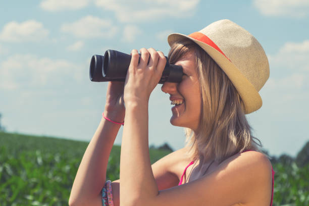 istock Young woman looking through binoculars in the nature. 905953196