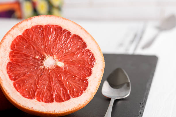 istock Grapefruit with spoon on black stone background on white wooden table 905954198