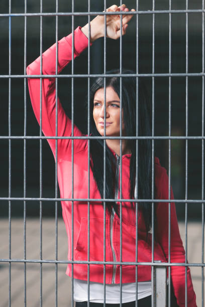 istock Young woman looking from behind the bars 905956872