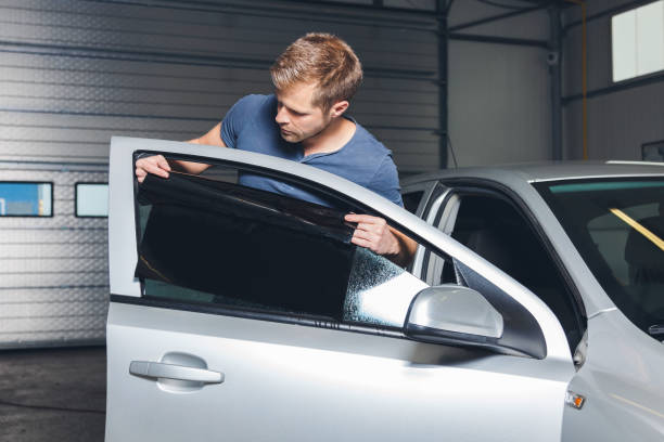 Applying tinting foil onto a car window Applying tinting foil onto a car window in a workshop uv protection photos stock pictures, royalty-free photos & images