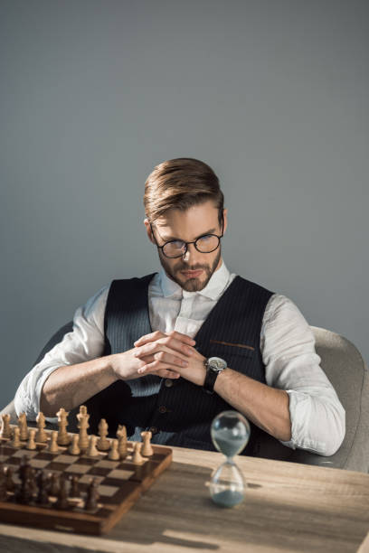 istock concentrated young businessman looking at sand clock while playing chess 905969380